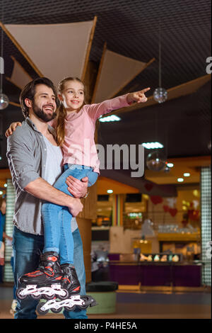 Lächelnd Vater Holding Tochter in Rollschuhen auf Roller Rink Stockfoto