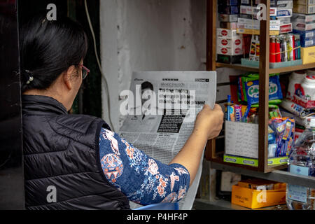 Hanoi, Vietnam - März 16, 2018: Lokale Frau liest eine Zeitung auf der Straße Stockfoto