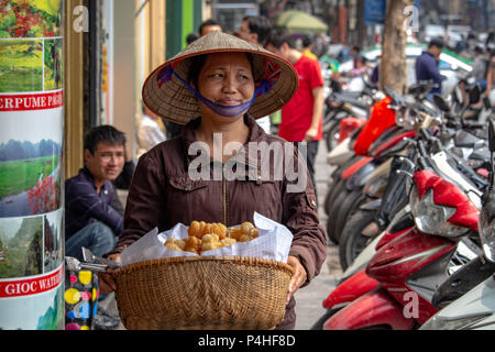 Hanoi, Vietnam - 16. März 2018: Frau verkaufen gebratene Spezialitäten und Desserts auf der Straße Stockfoto