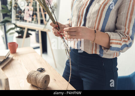 7/8-Ansicht von weiblichen Händen mit trockenen Blumen und Garn Stockfoto
