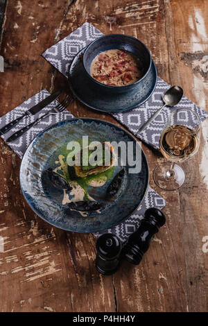 Köstliche creme Suppe, gebratener Fisch und Glas Wein auf hölzernen Tisch im Restaurant Stockfoto