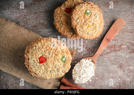 Hausgemachte oatmeal Cookies, Zimtstangen und einen Löffel mit Haferflocken auf einer hölzernen Hintergrund Stockfoto