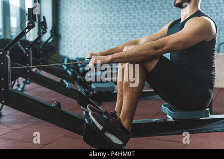 Zugeschnittenes Bild der Sportler tun Übung auf rudergerät im Sportzentrum Stockfoto