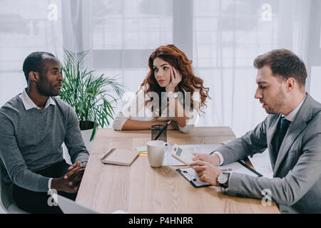 Finanzberater tut Berechnung während der Business Partner am Tisch sitzen Stockfoto