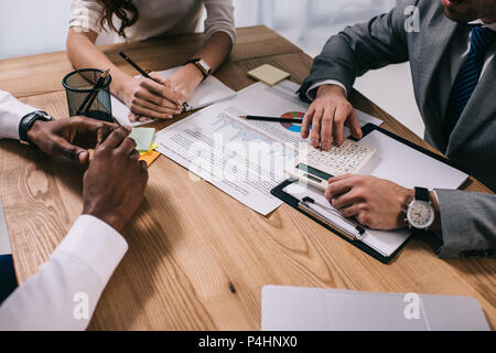 7/8-Ansicht von Geschäftsleuten am Tisch mit Papieren und Rechner sitzen Stockfoto