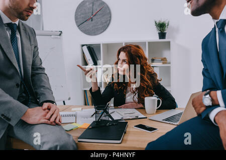 7/8-Ansicht von zwei Geschäftsleute sitzen am Tisch und Manager mit dem Finger zeigend Stockfoto