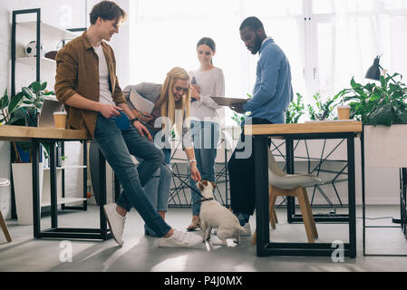 Multikulturellen Kollegen mit Lehrbüchern und Jack Russel Terrier an der Leine in modernen Büro Stockfoto