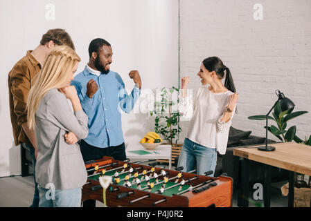 Zwei Kollegen feiern Sieg im tischfussball vor Kollegen zu verlieren. Stockfoto