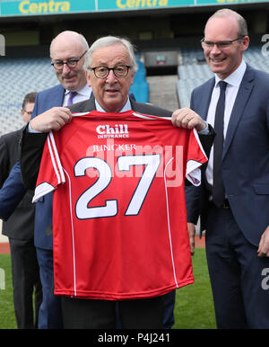 Der Präsident der Europäischen Kommission, Jean-Claude Juncker Holding einen Korken Jersey (Mitte) mit EU-Kommissar für Landwirtschaft und ländliche Entwicklung Phil Hogan (links) und Minister für Auswärtige Angelegenheiten Simon Coveney (rechts) bei einem Besuch in der Heimat der Gaelic Athletic Association im Croke Park. Stockfoto