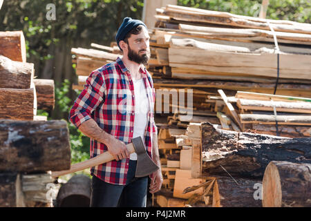 Holzfäller in kariertem Hemd mit ax Bärtigen am Sägewerk Stockfoto