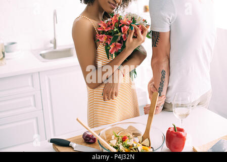 7/8 Schuß von junge Frau mit Blumenstrauß und Freund mit tätowierten Hand stehen in der Nähe von Küche Stockfoto