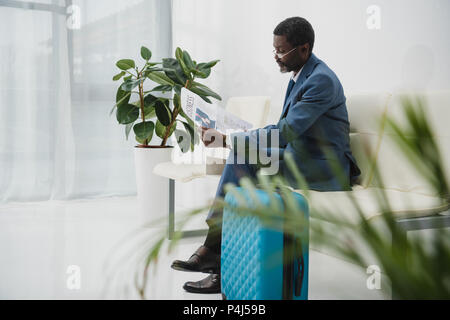 Im mittleren Alter Geschäftsmann sitzt im Wartezimmer und lesen Zeitung Stockfoto