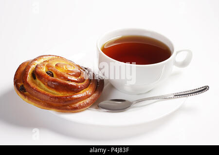 Brötchen mit Rosinen und Tasse Tee in der Platte auf weißem Hintergrund Stockfoto