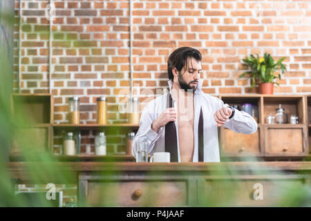 Stattliche Einzelgänger Geschäftsmann mit Aufgeknöpfte Hemd Kontrolle Zeit Küche Stockfoto