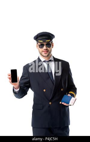 Portrait von Pilotprojekten in Uniform mit Pass und Ticket in der Hand zeigt Smartphone mit leerer Bildschirm isoliert auf weißem Stockfoto