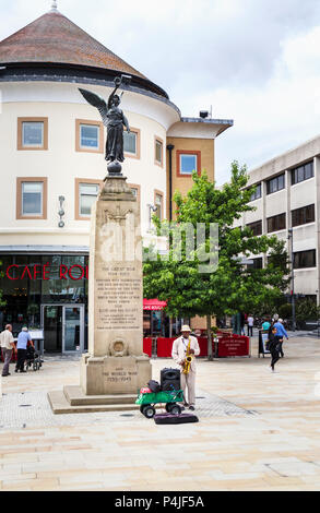 Gaukler spielen ein Saxophonist vom War Memorial in Jubilee Square outside cafe Rouge, Stadtzentrum von Woking, Surrey, Südosten, England, Grossbritannien Stockfoto