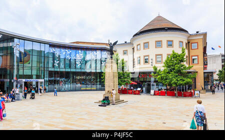 Gaukler spielen ein Saxophonist vom War Memorial in Jubilee Square durch den Pfauen Einkaufszentrum außerhalb Café Rouge, Stadtzentrum von Woking, Surrey, Großbritannien Stockfoto