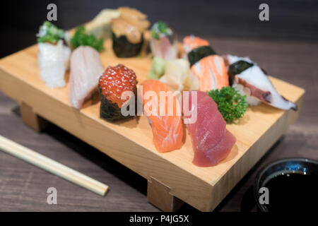 Close-up Sushi und Sashimi auf Holzplatte auf schwarzem Holz- Tabelle gemischt. Japanisches Essen. Stockfoto