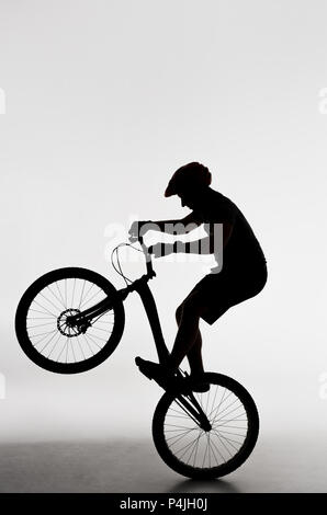Silhouette des Versuches Biker stehen auf Hinterrad auf Weiß Stockfoto