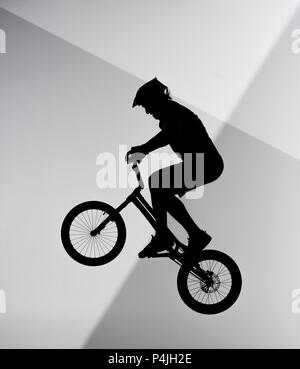 Silhouette des Versuches Radfahrer springen auf dem Fahrrad auf abstrakte grauen und weißen Hintergrund Stockfoto