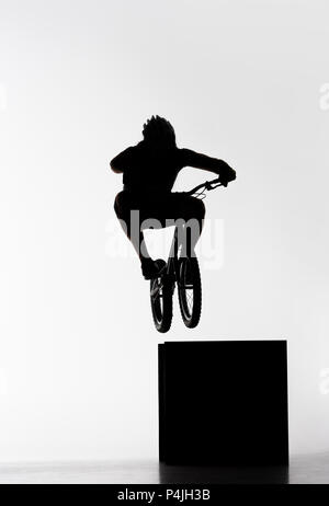 Silhouette des Versuches biker Springen auf Cube auf Weiß Stockfoto