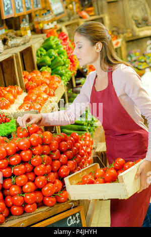 Shop Mitarbeiter tragen eine Kiste Tomaten Stockfoto