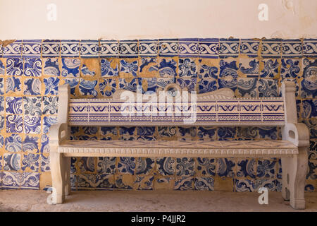 Sitzbank und eine Wand mit traditionellen Keramik Azulejos, Fliesen mit floralen Motiven. Kirche der Nossa Senhora da Rocha, Algarve, Portugal. Stockfoto