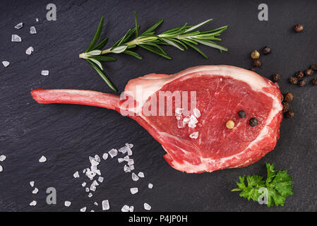 Frische Lammkotelett mit Rosmarin, Salz und Pfeffer auf dem schwarzen Stein. Fleisch, Ansicht von oben Stockfoto