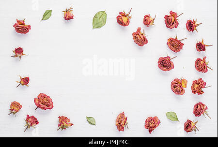 Getrocknete Rosen Blumen auf Vintage rustic weiß Schreibtisch aus Holz als Hintergrund. Ansicht von Oben. Konzept der Liebe und der romantischen und der Lauf der Zeit. Stockfoto