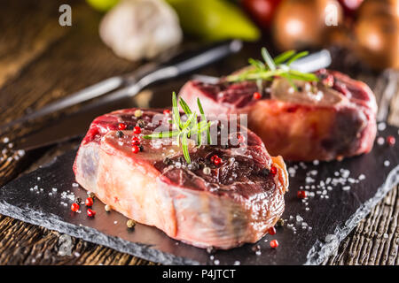 Zwei Stücke rohes Rindfleisch Schaft auf Schiefer und Holz- Tabelle. Stockfoto