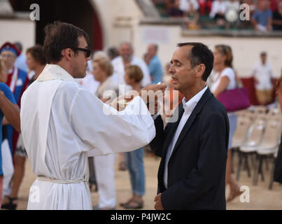 August 12, 2015 - Beziers, Frankreich: Beziers Bürgermeister Essen sakramentalen Brot während Eine katholische Messe in der stierkampfarena vor der Eröffnung der "Feria", ein Sommerfest der Straßenfeste und Stierkampf. Neuer Bürgermeister der Stadt, Robert Menard, hat die große öffentliche Masse in der Arena im Rahmen seiner kommunalen Programm katholischen Traditionen der Stadt neu zu beleben, erlaubt. Le Maire de Beziers Robert Menard recoit l'hostie Pendant la Messe en plein air Dans Les Arenes de Beziers qui vorausgehen. l'Ouverture de La Corrida. Stockfoto