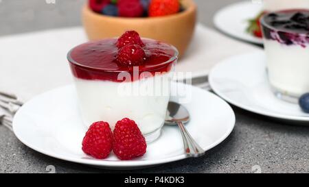 Joghurt mit Himbeeren und Himbeere flavoured Jam. Holz- schale frische reife Waldfrüchte im Hintergrund Stockfoto