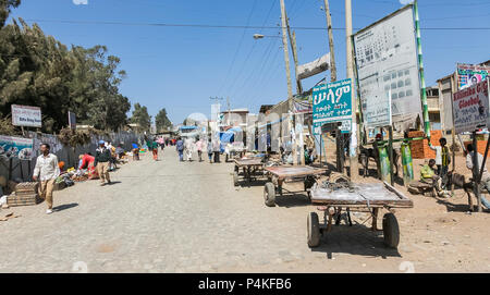 Addis Abeba, Äthiopien, 30. Januar 2014, Eselskarren auf einem belebten Markt gesäumten Straße als Fußgänger Einkaufen Stockfoto