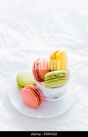 Sortierte bunte Macarons in einer Tasse Tee Stockfoto