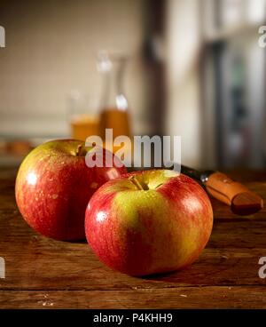 Rote Äpfel auf einem Holztisch und Apfelsaft im Hintergrund Stockfoto