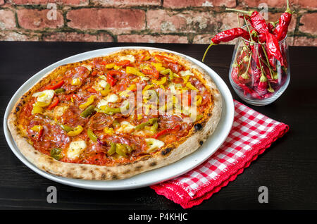 Pizza mit Sauerteig Base, Tomatensauce mit Oregano und Olivenöl, Mozzarella, grüne, gelbe und rote Paprika, würzige Salami, Salami, Chorizo Stockfoto