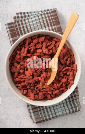 Getrocknete gogyberries in eine Schüssel geben und mit einem Holzlöffel Stockfoto