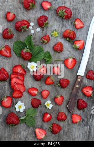 Frische Erdbeeren, ganz und halbiert, auf einer hölzernen Oberfläche Stockfoto