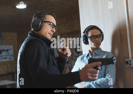 Männliche Kursleiter verweist auf etwas in Shooting Gallery Stockfoto