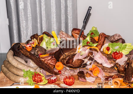 Essen Fach mit leckeren Salami, Schinken, Würstchen, Tomaten, Salat und Gemüse - Fleischplatte mit Auswahl - Schneiden von Wurst und Heilung Stockfoto