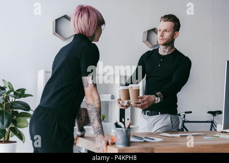 Hübscher junger Geschäftsmann, Pappbechern Kollegin im Büro Stockfoto