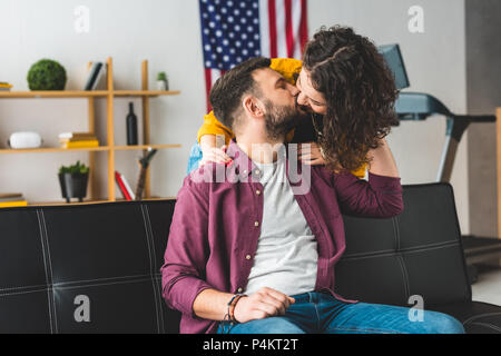 Mann küssen Freundin beim Sitzen auf einem Ledersofa Stockfoto