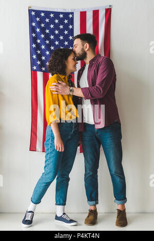 Mann küssen Freundin Stirn vor der Wand mit amerikanischer Flagge Stockfoto