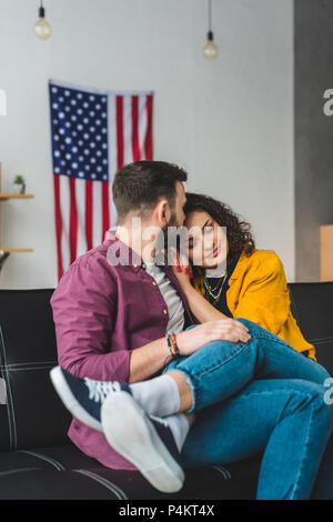 Frau sitzt auf der Freund Knie, während er ihre Stirn küssen Stockfoto
