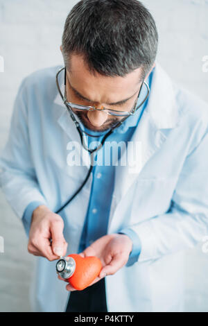 Hohe Betrachtungswinkel und der Arzt hört Herzschlag von Spielzeug Herz mit stethoskope Stockfoto