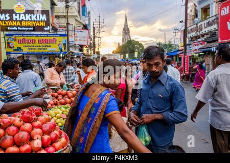 Ein Mann und eine Frau Obst kaufen, mit Unserer Lieben Frau von Lourdes Kirche im Hintergrund, Netaji Subhas Chandra Bose Rd, Tiruchirappalli, Tamil Nadu, Indien. Stockfoto