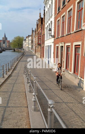 Brügge, Belgien - 20 April 2014: eine junge Frau mit dem Fahrrad entlang Langerei Kanal und traditionellen Fassaden Stockfoto