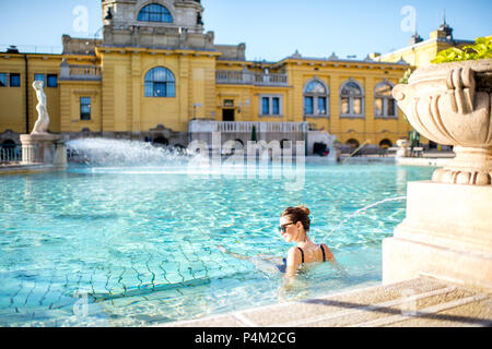 Ungarn, Budapest - Mai 21, 2018: Junge Frau entspannend mit Wasserstrahl auf das berühmte Széchenyi Thermalbäder in Budapest. Es ist eine der größten nat Stockfoto