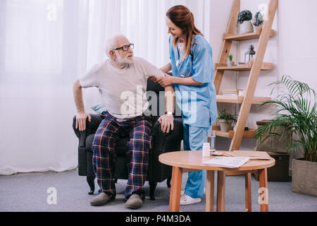 Krankenschwester, die ältere Menschen aufstehen helfen Stockfoto