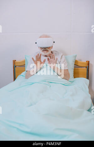 Ältere Männer im Krankenhaus Bett mit Virtual reality Headset Stockfoto